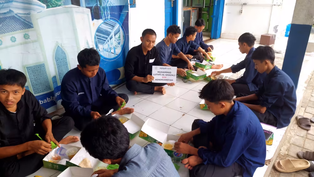 Para santri sedang menikmati paket aqiqah yang telah dibagikan.